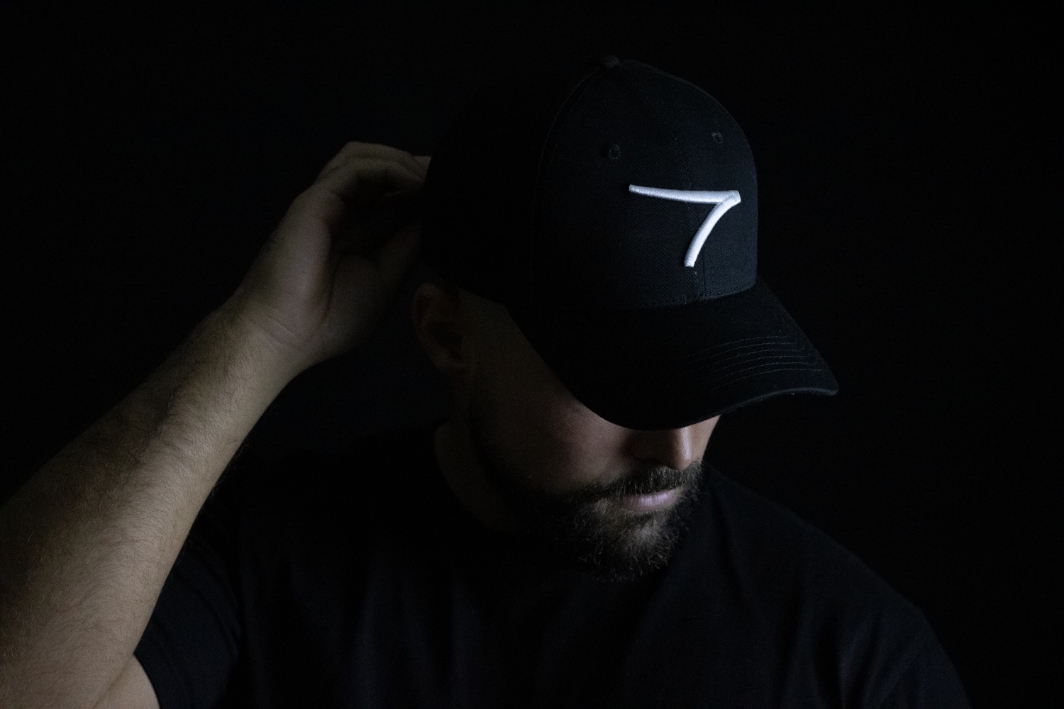 Dark scene with young man wearing black fable golf cap